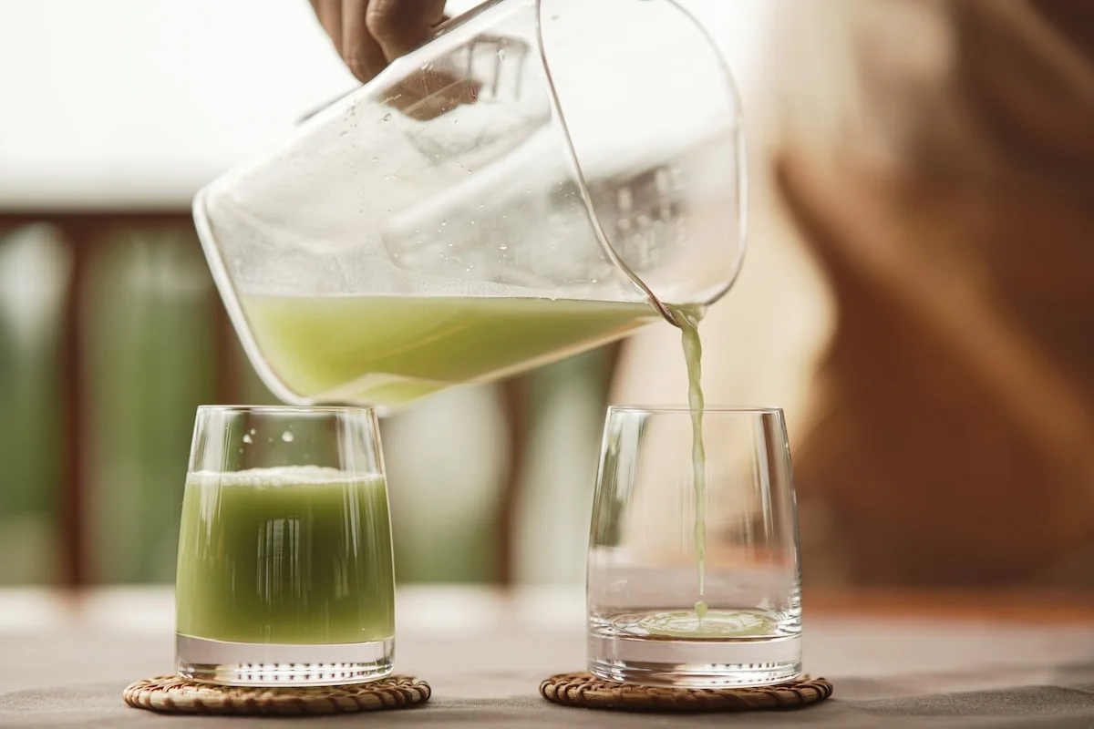 Fresh green juice being poured into a glass