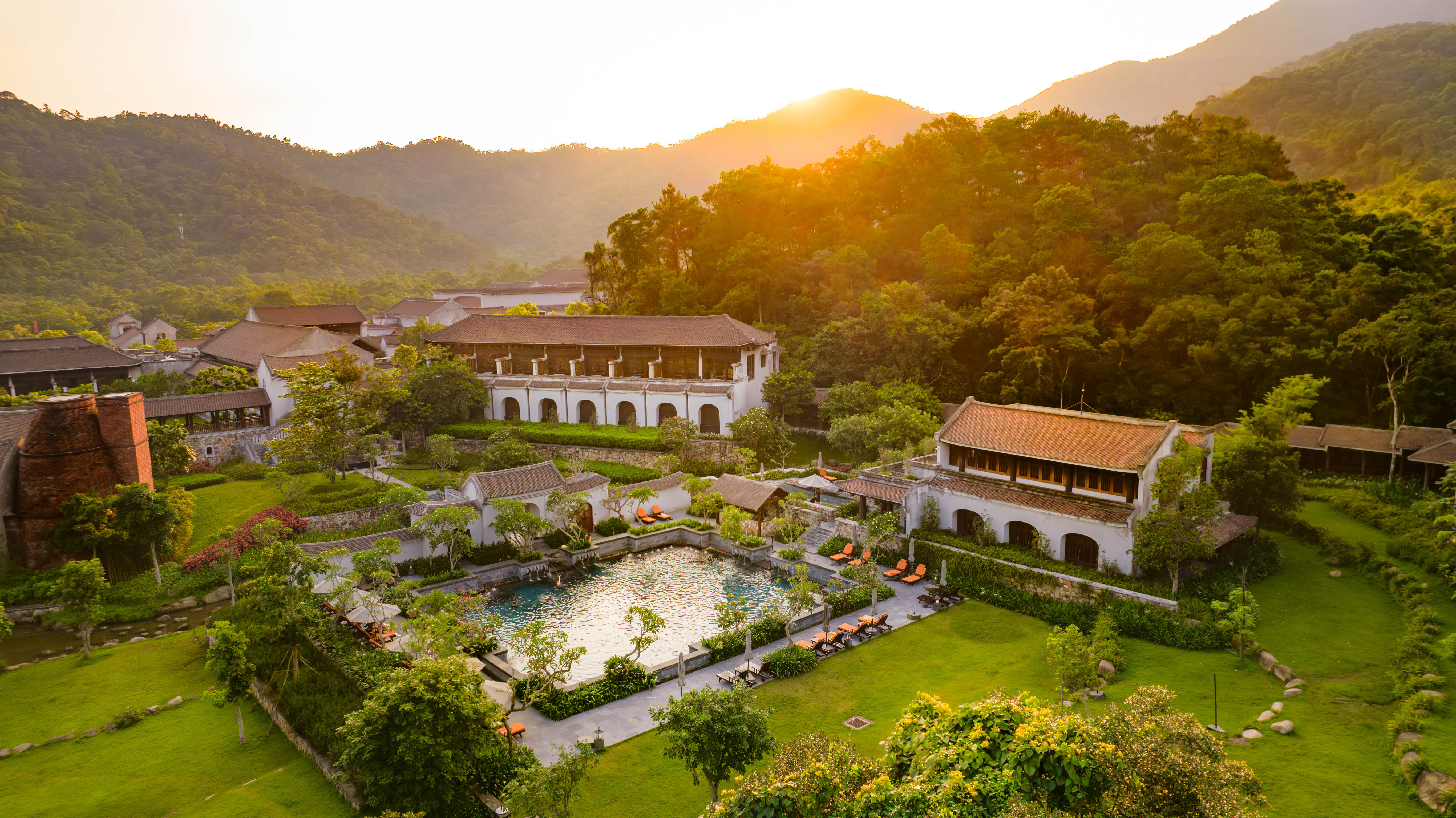 Legacy Yên Tử at golden hour — resort, pool and gardens held inside the mountain valley